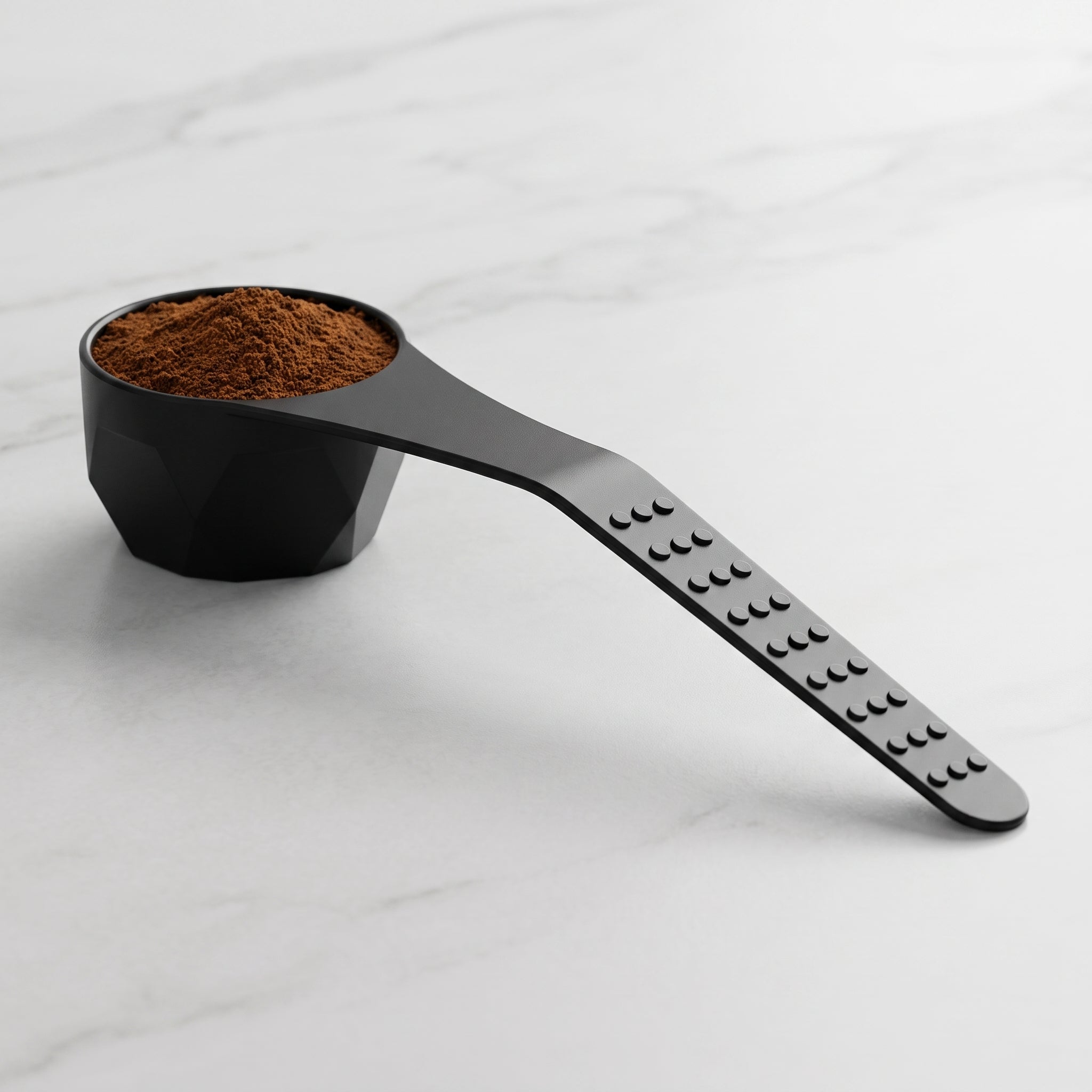 İmzapack siyah plastik cezve ve kahve ölçü kaşığı. Görseldeki orijinal tasarımıyla ışığı yansıtan elmas kesim (fasetalı) derin hazne, ergonomik açılı sap ve kaymayı önleyen kabartmalı noktalı tutma yüzeyi. Türk kahvesi, filtre kahve ve espresso tozlarını hassas porsiyonlamak için tasarlanmış d